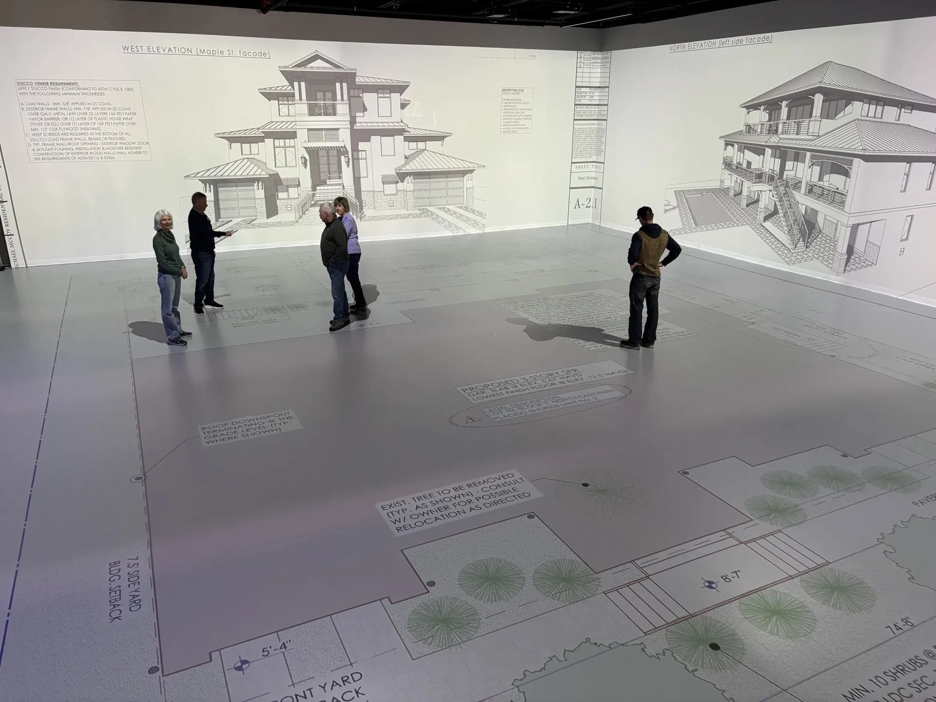 Projective Studios — clients reviewing projected elevations and floor plan at full scale
